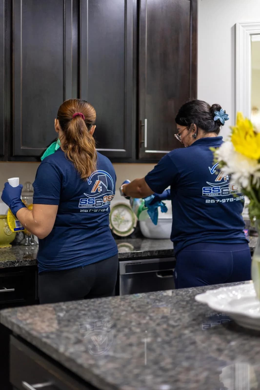 Close-up of cleaning staff member at work, gloves and spray bottle